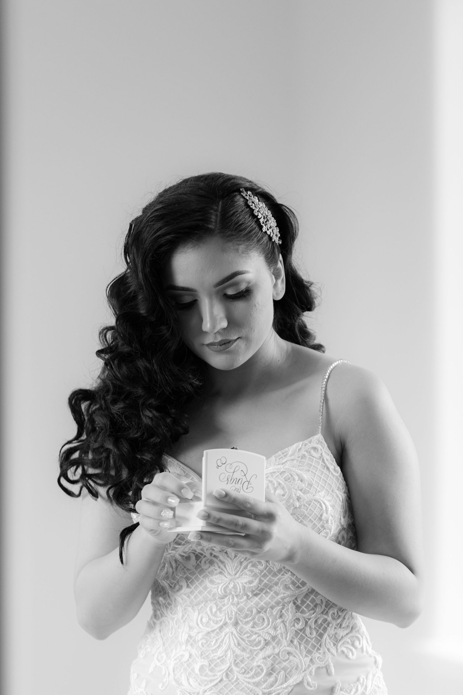 Black and white photo series showing a person in a white lace dress looking down at something in their hands.