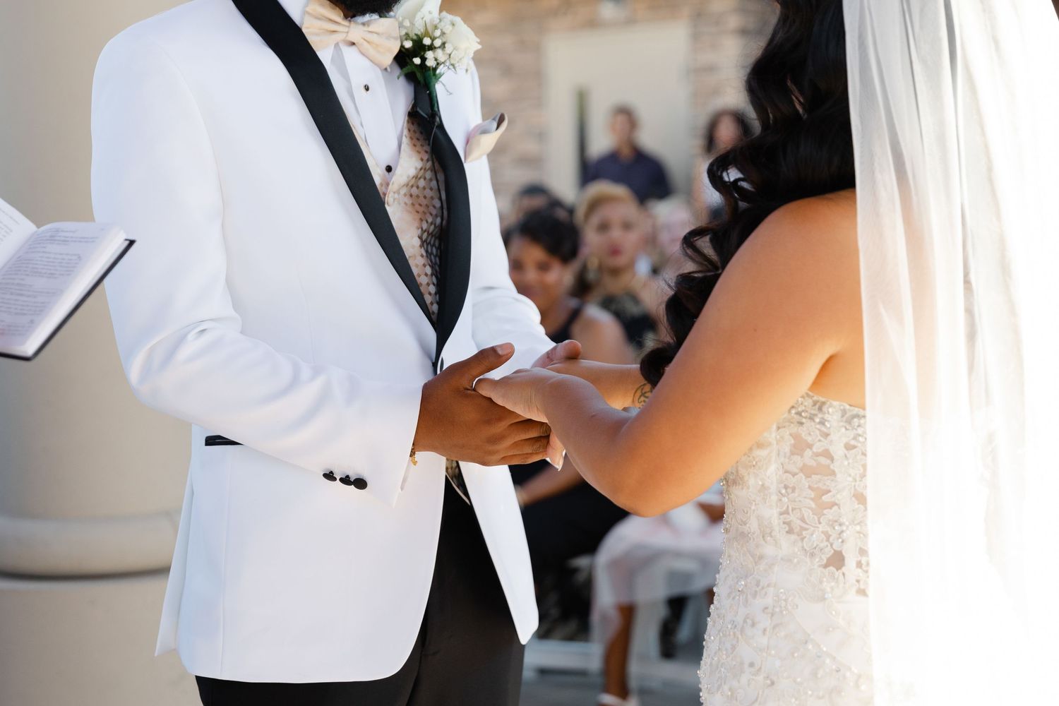 A couple in wedding attire shares a romantic dance at their reception, surrounded by white decor.