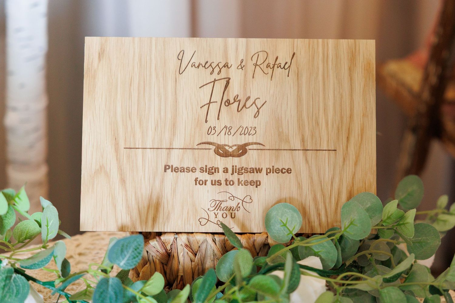 Wooden wedding signs with greenery decor displayed on rustic shelves at a reception venue.