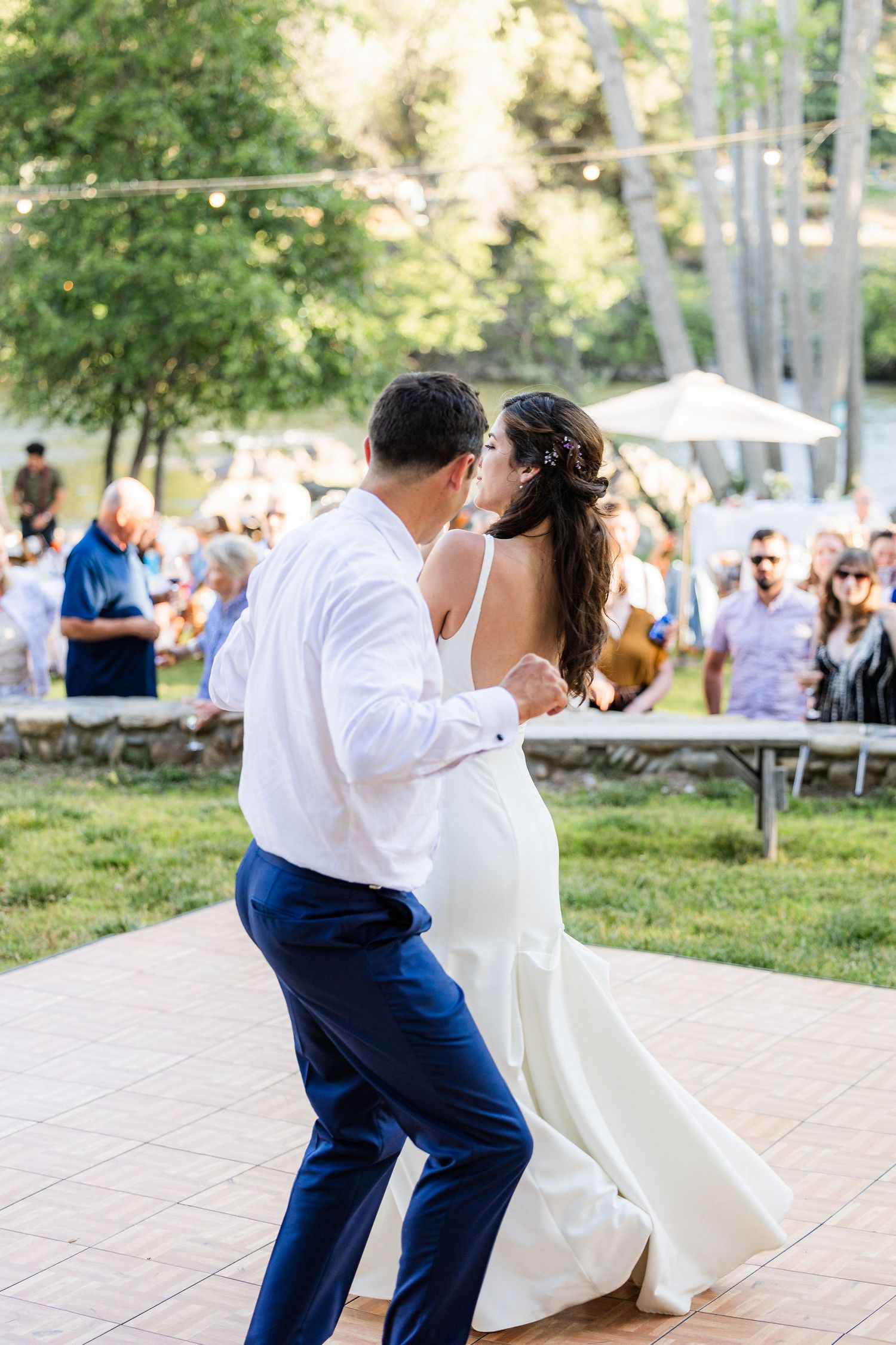 A couple performs a romantic dip dance move during their wedding reception on an outdoor patio.