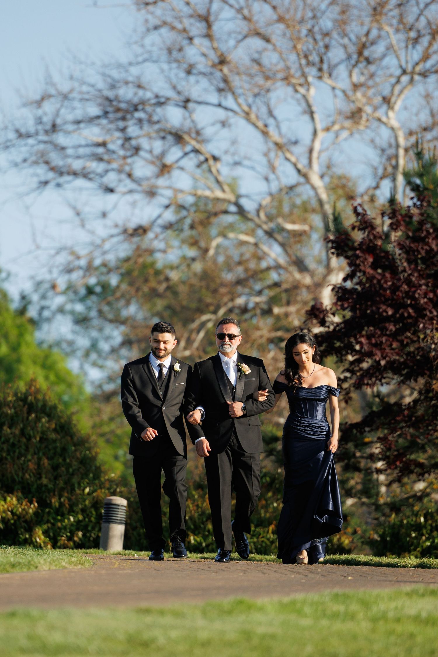 Wedding party walking together on a grassy hill during an outdoor autumn ceremony.