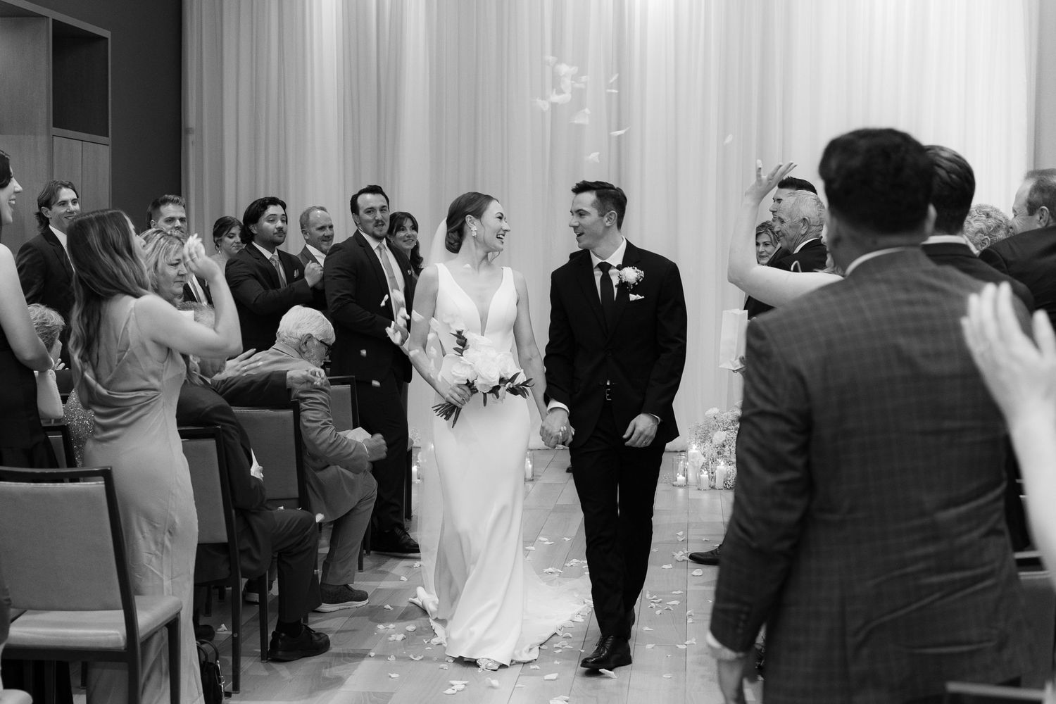 A wedding ceremony in progress with guests seated in rows watching the couple at the altar.