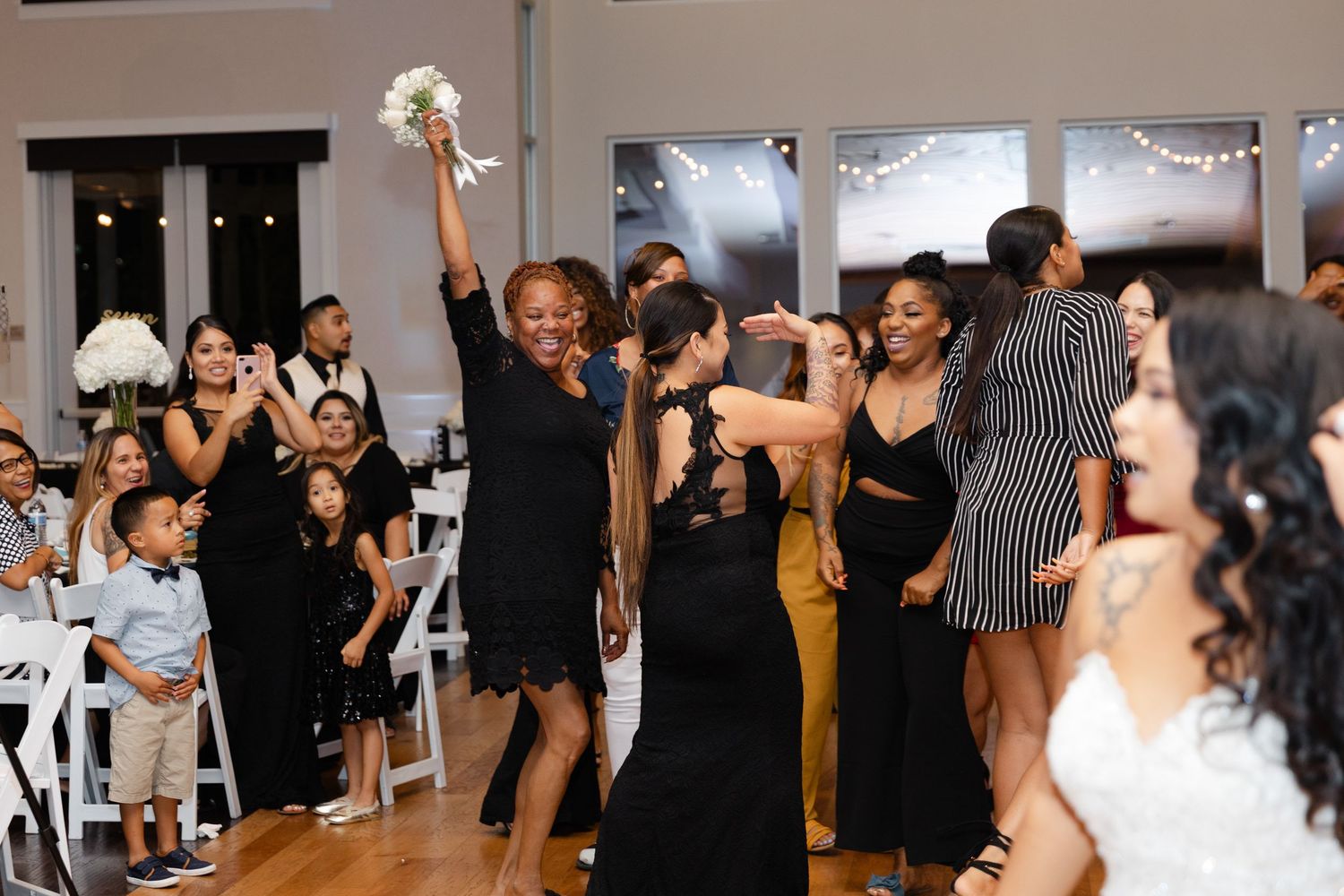 Energetic group of dancers moving together in a dance studio with white walls and wooden floors during a class.