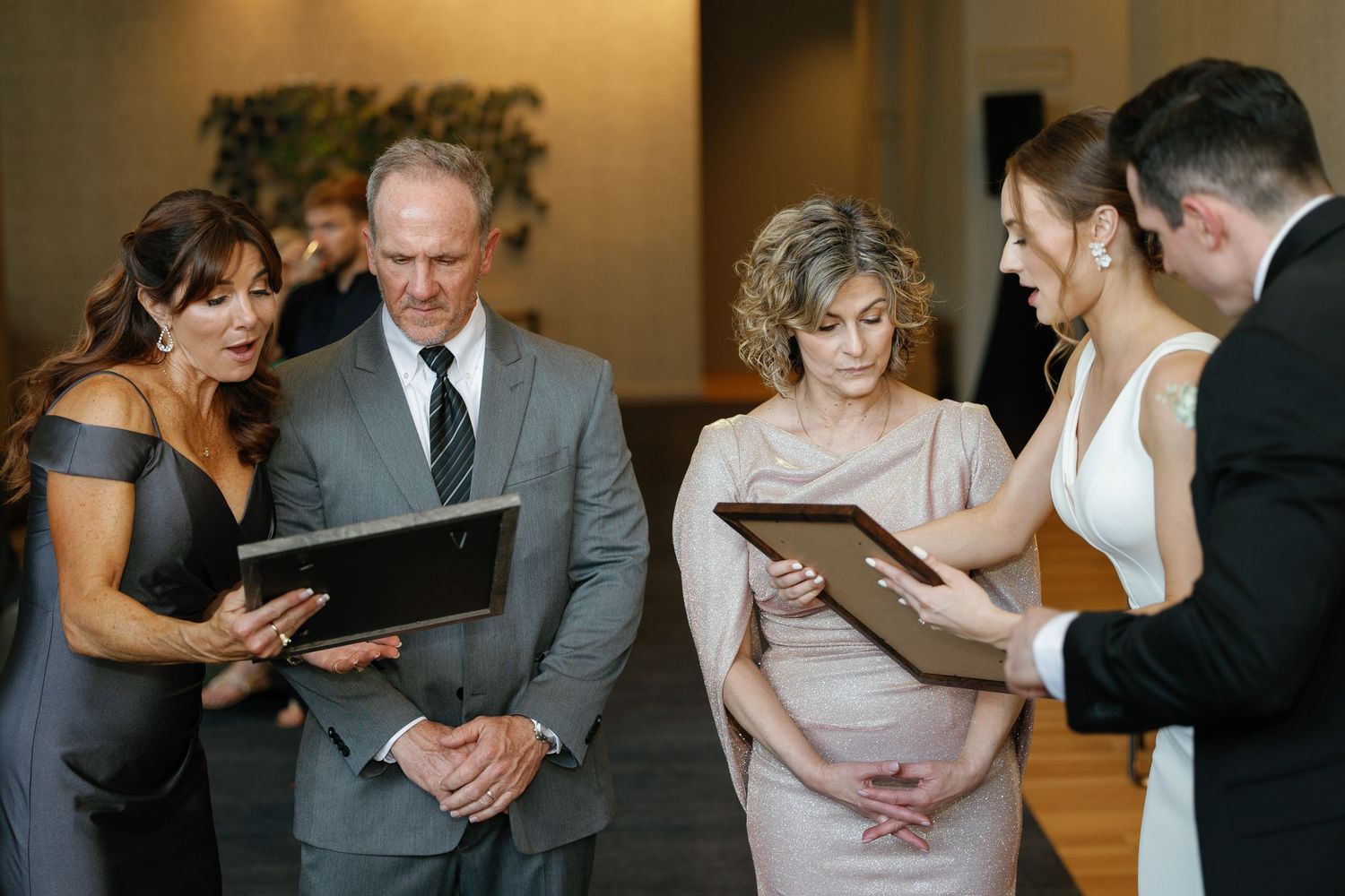 A group of formally dressed people stand together reading from large books during what appears to be a ceremony.