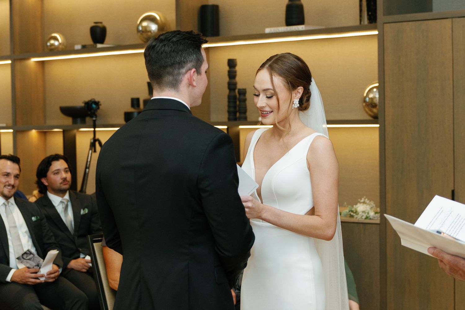 A group of wedding guests stand together in a formal venue during an elegant ceremony.