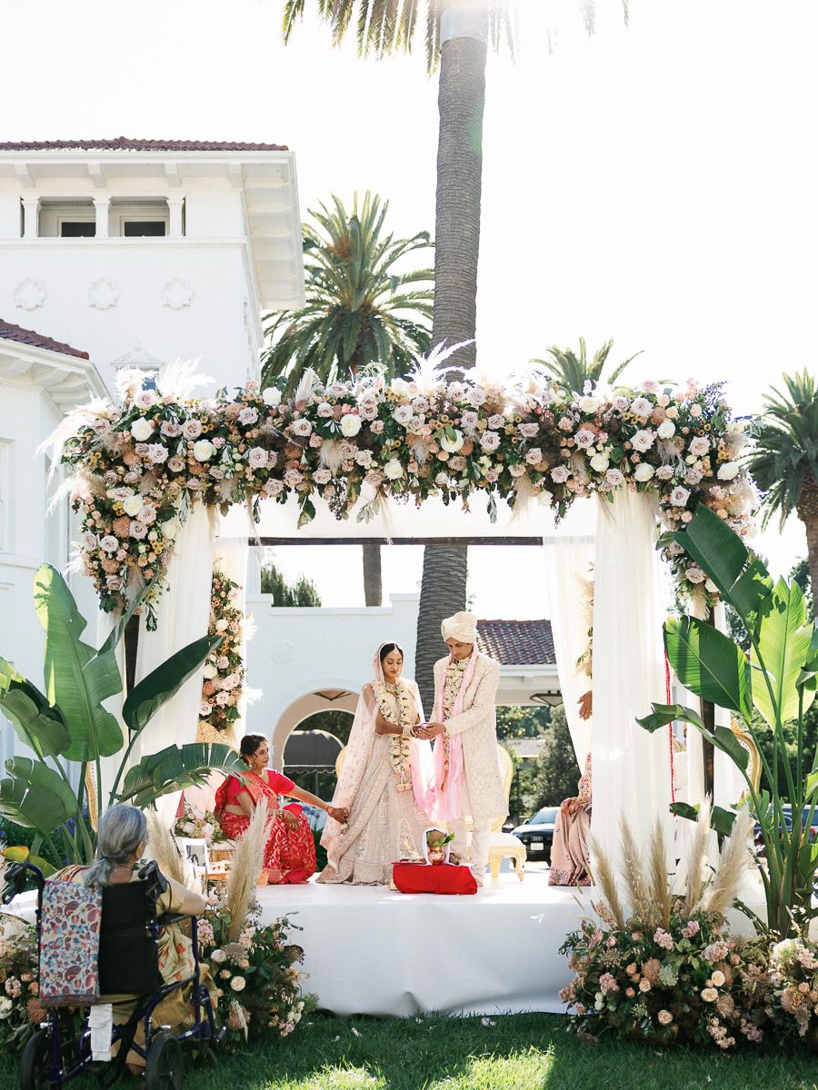 Outdoor wedding ceremony setup with tropical palm trees and floral arch decorations.