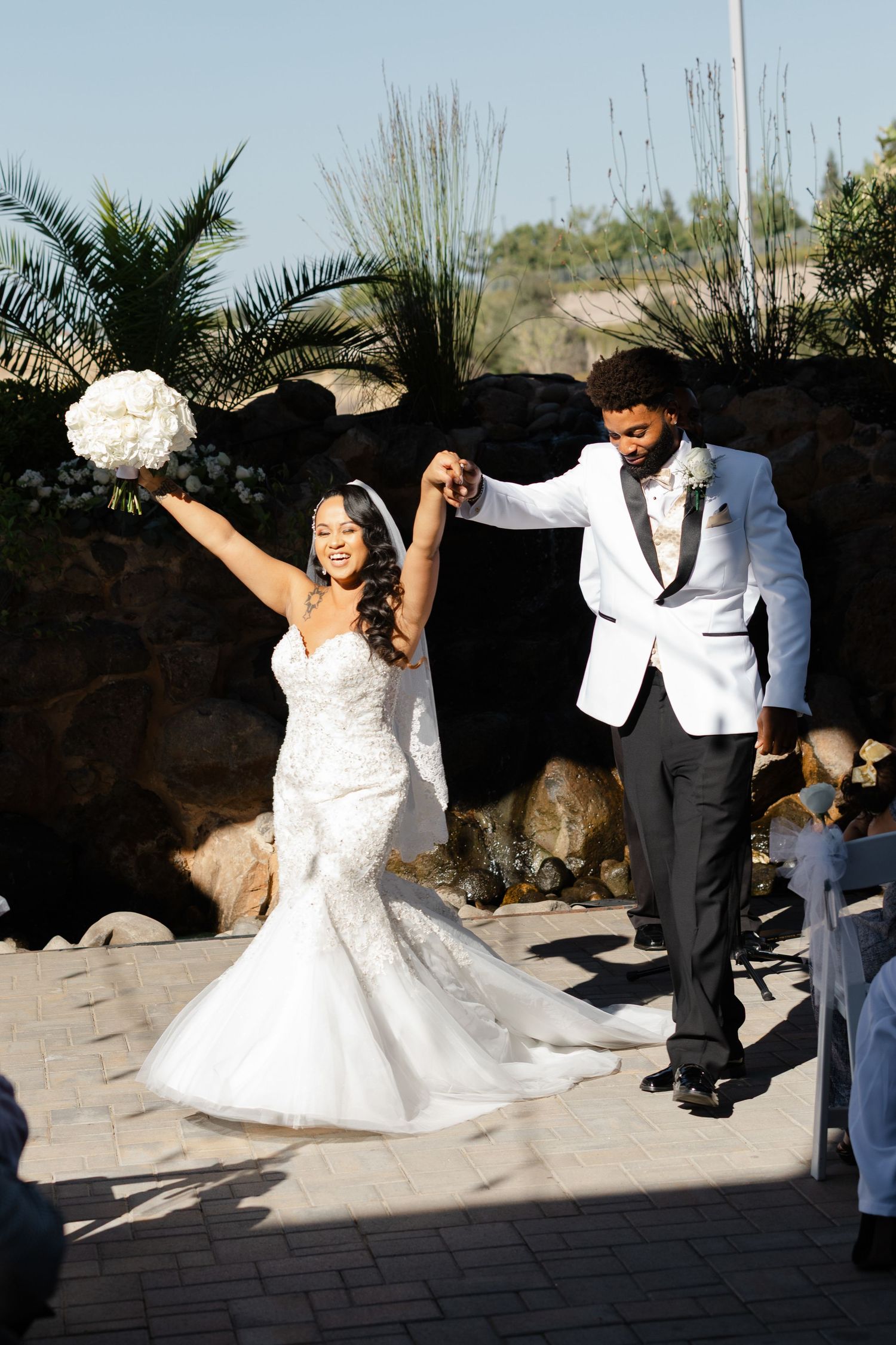 A sequence of wedding photos showing a couple dancing and twirling in a sunny outdoor garden setting with palm trees.