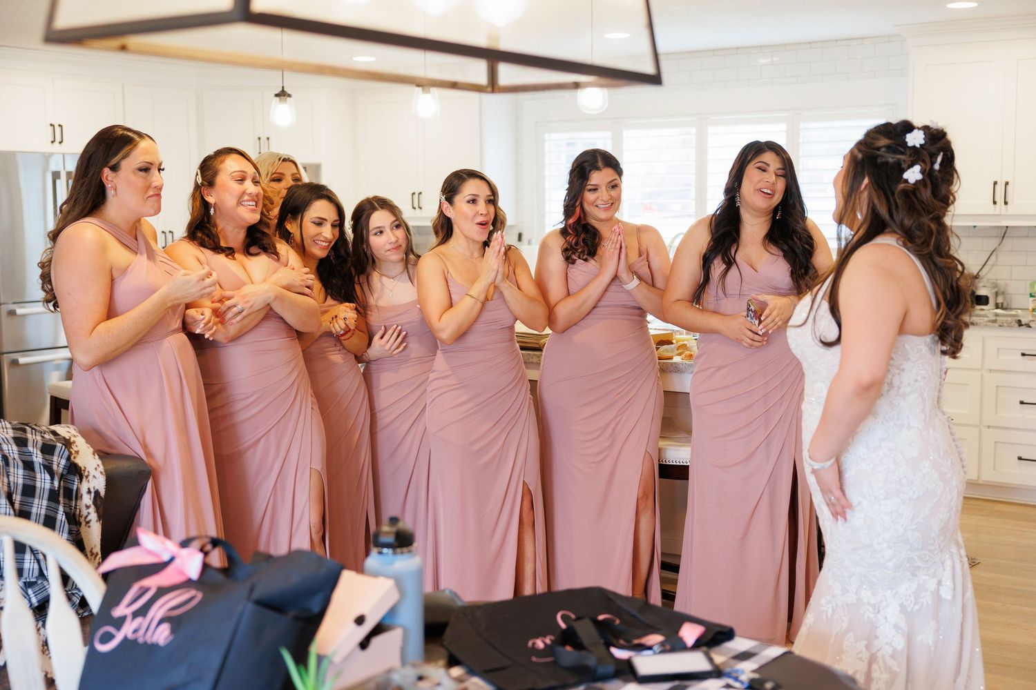 Bridesmaids in matching dusty rose dresses share a candid moment together during wedding preparations.