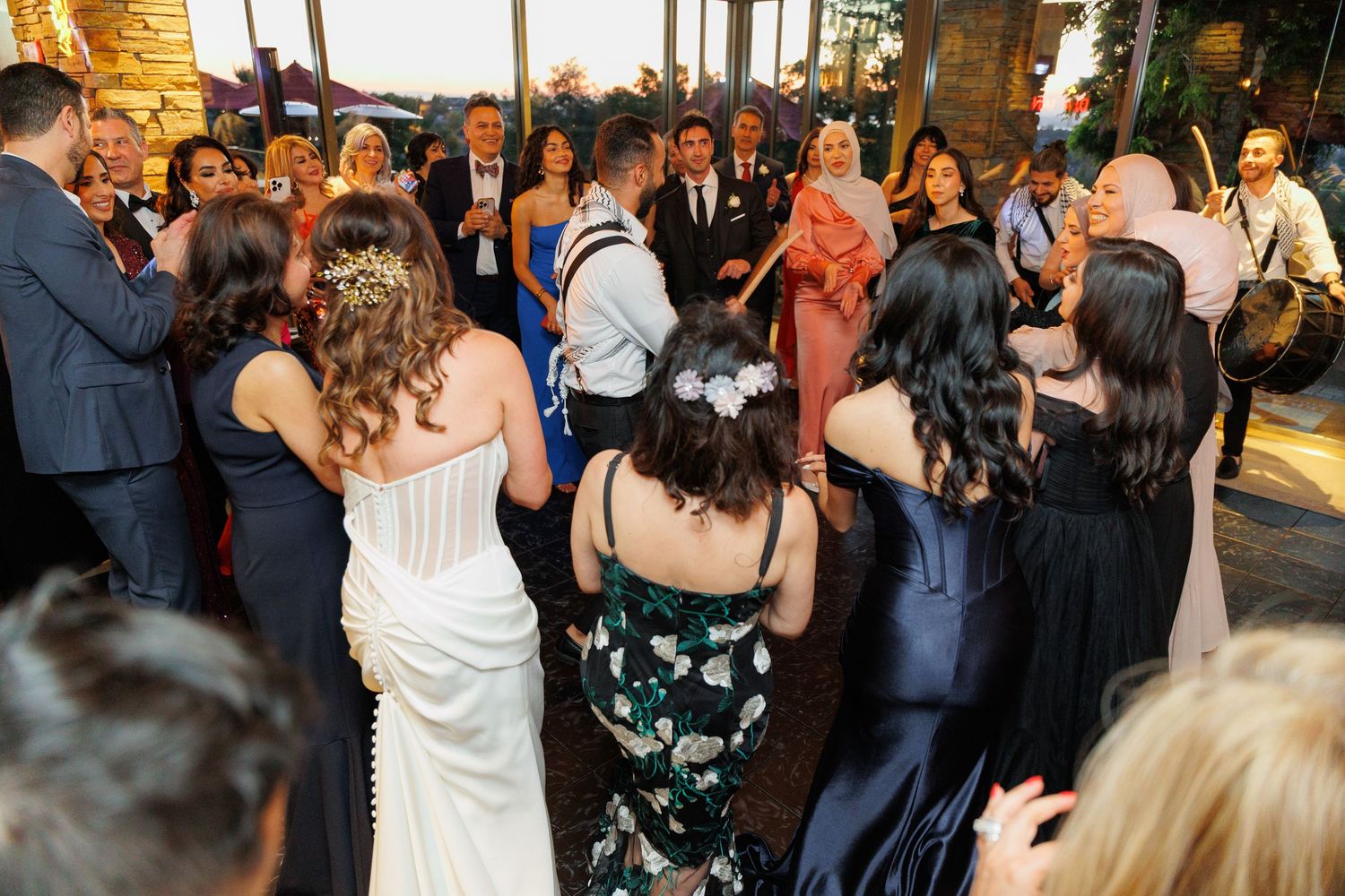 Wedding guests dance together on a crowded reception dance floor during an evening celebration.
