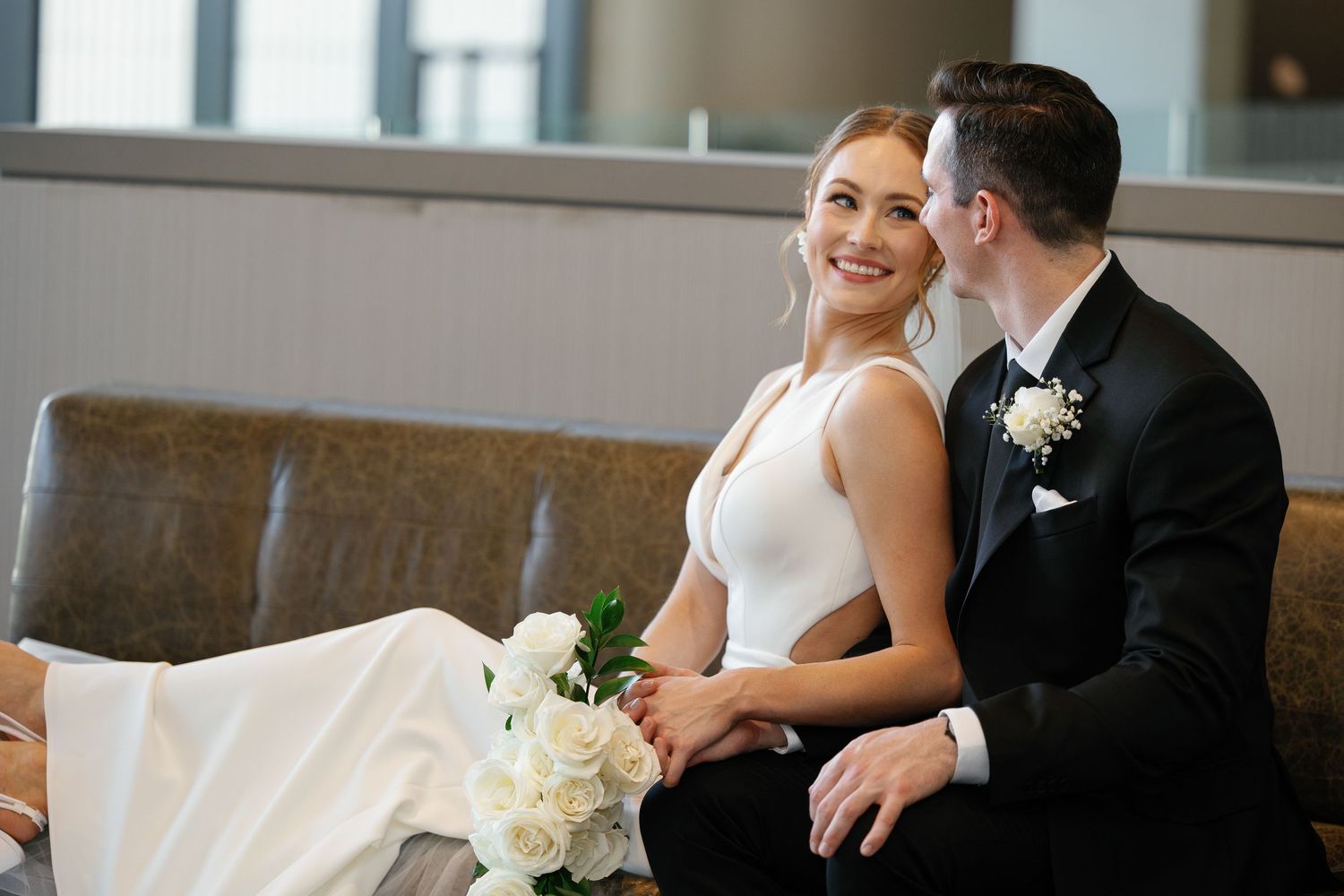 A bride in a white wedding dress and groom in black tuxedo share an intimate moment during their wedding celebration.