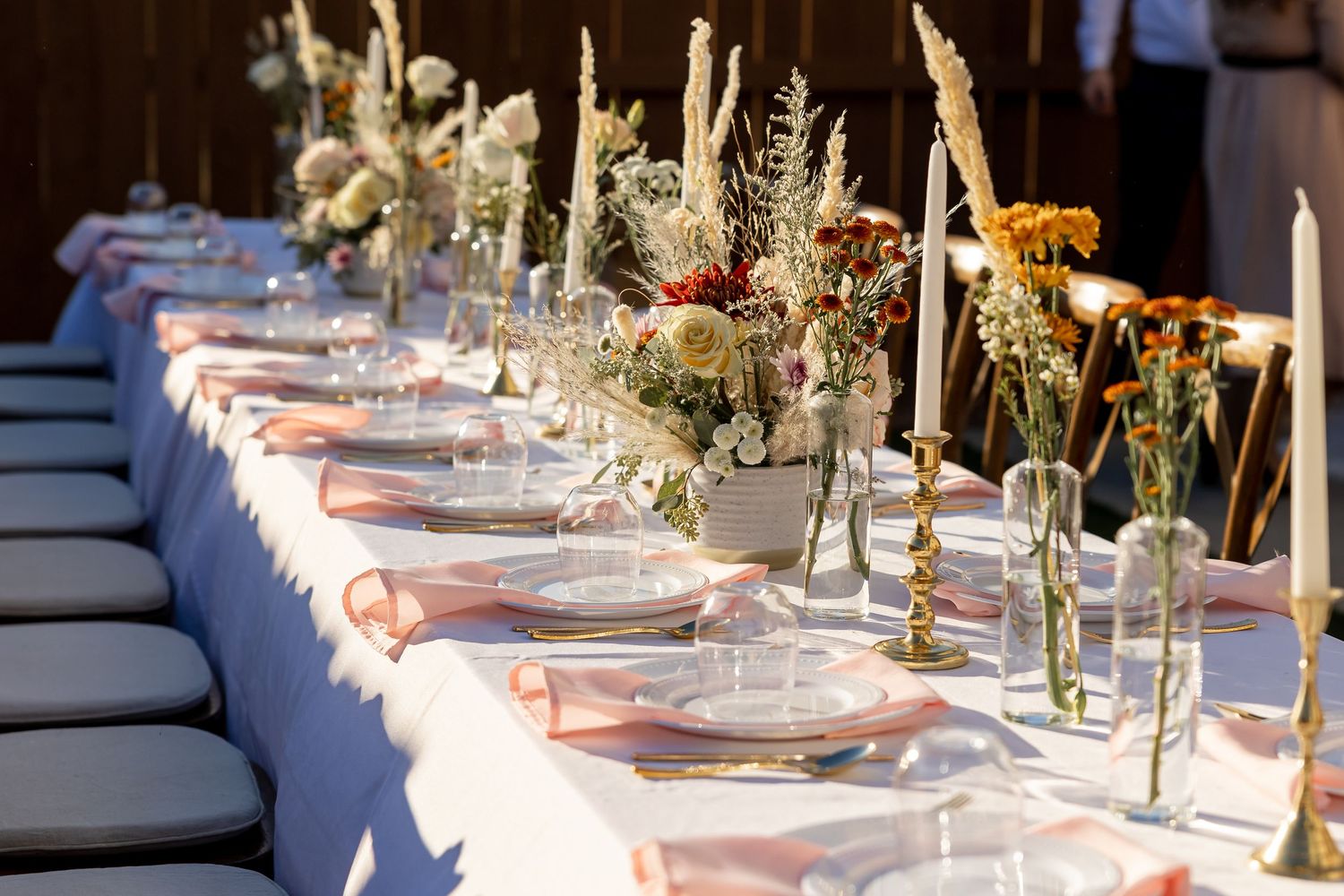 Elegant wedding table setting with white candles and delicate floral centerpieces.
