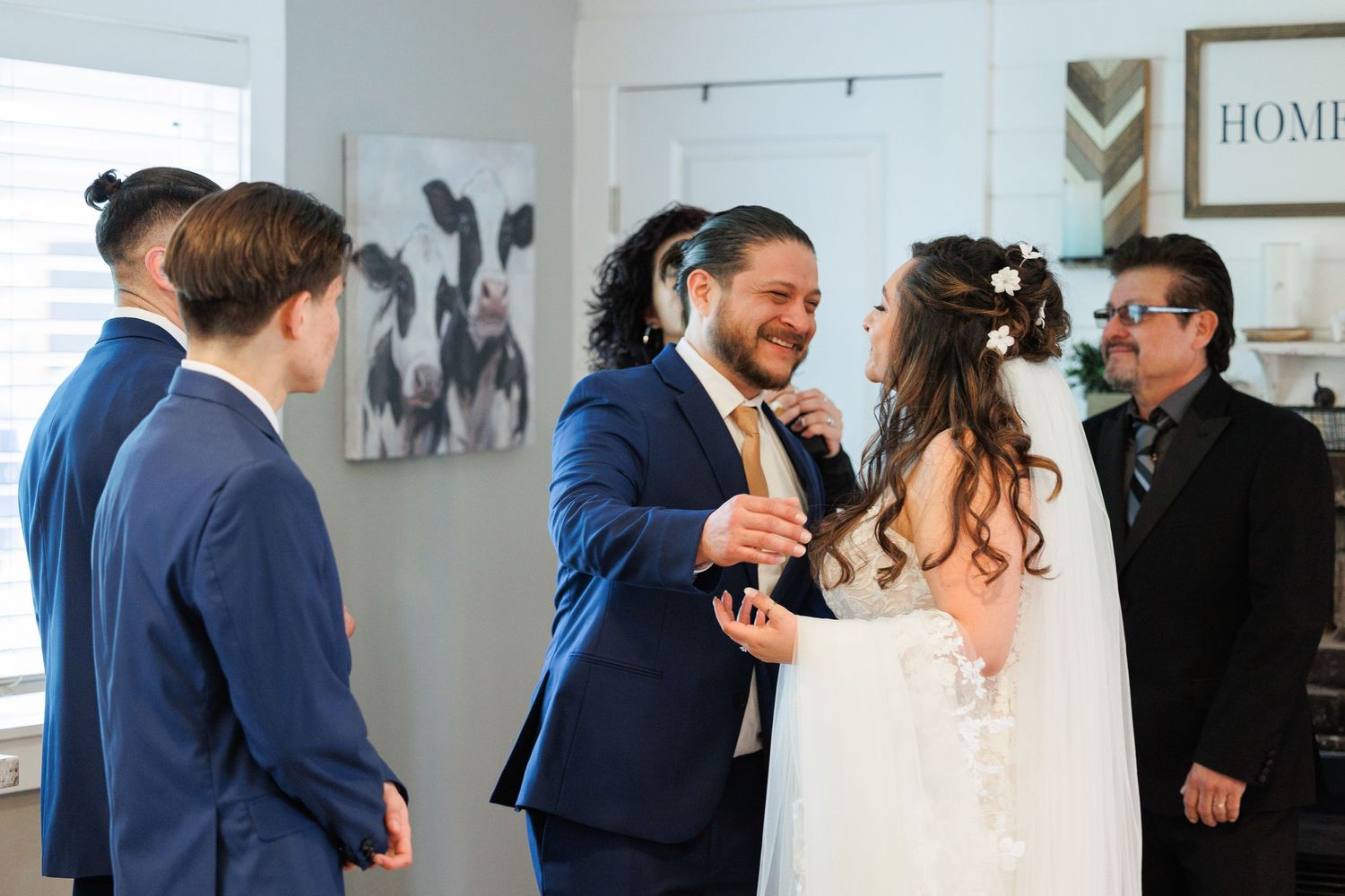 A joyful wedding celebration moment with the couple and guests sharing laughter in a light-filled room with farmhouse decor.