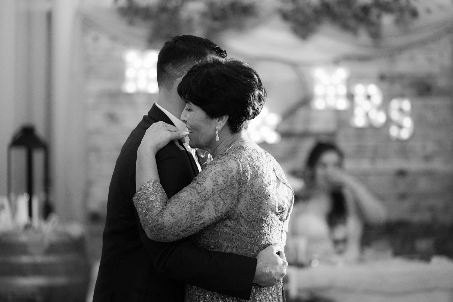 A couple in wedding attire embraces and dances together during their first dance at an elegant reception venue.