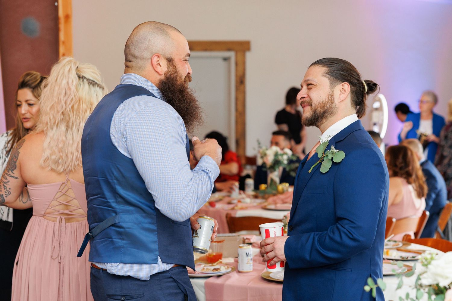 A couple shares a tender dance moment at a wedding reception in a warm-lit venue.