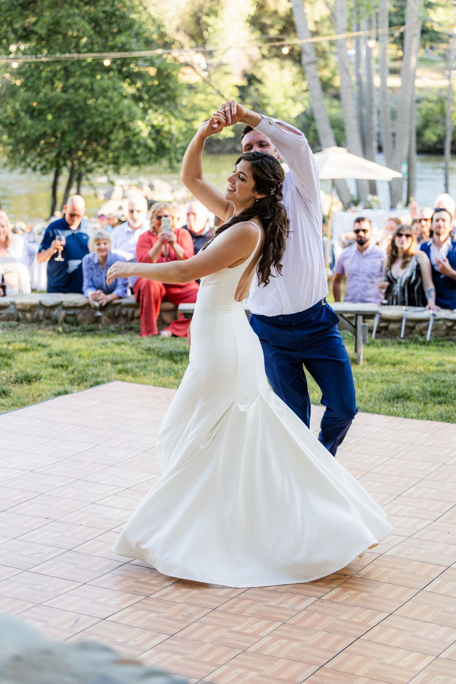 A couple performs an elegant dance spin on an outdoor patio as the bride's white dress twirls gracefully during their first dance.