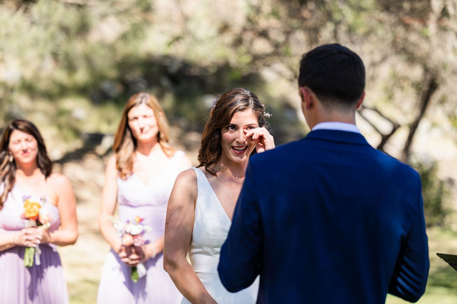 Wedding party laughs together outdoors during a candid moment in natural lighting.
