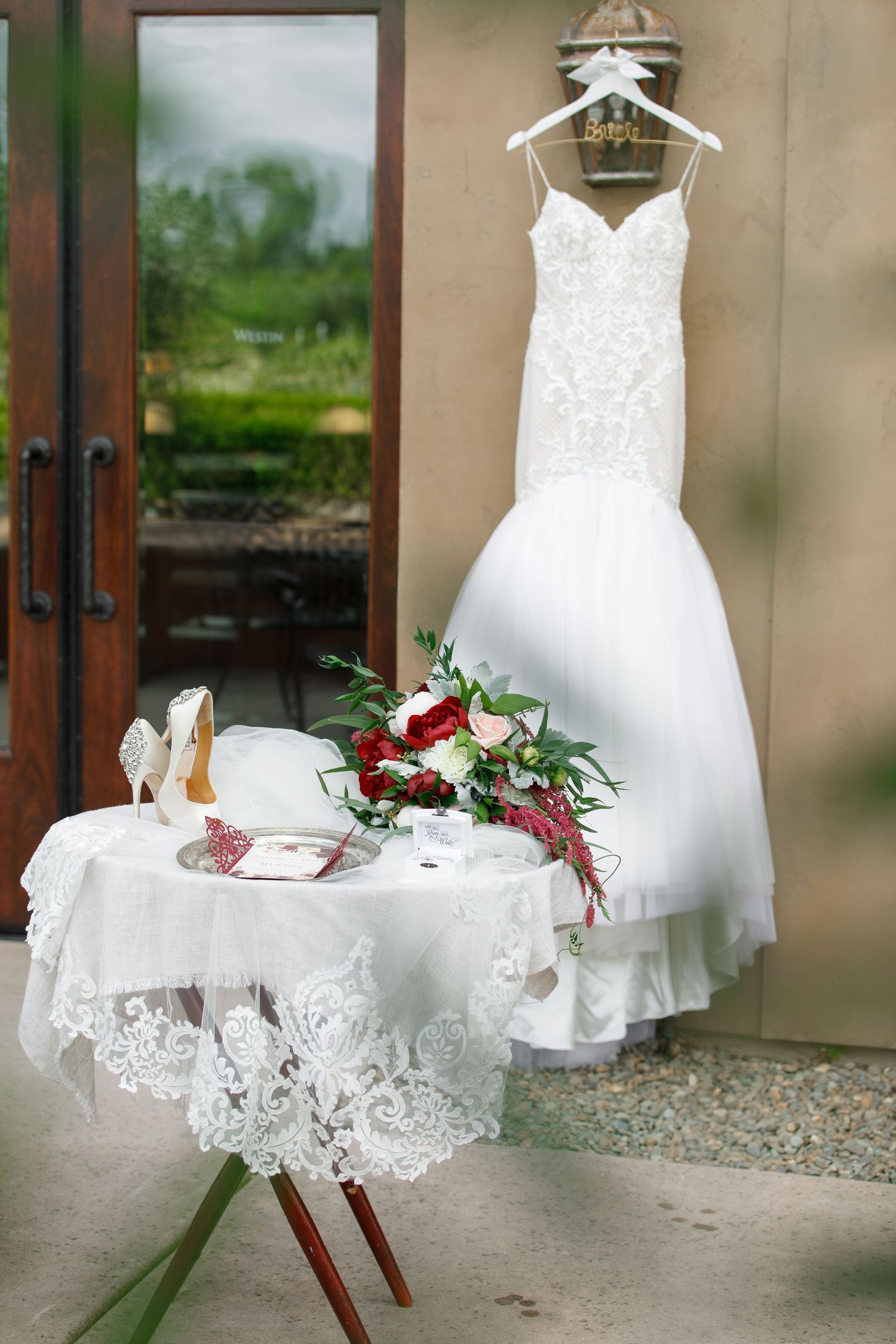A collection of white wedding dresses displayed on hangers with red floral accents and delicate lace details.