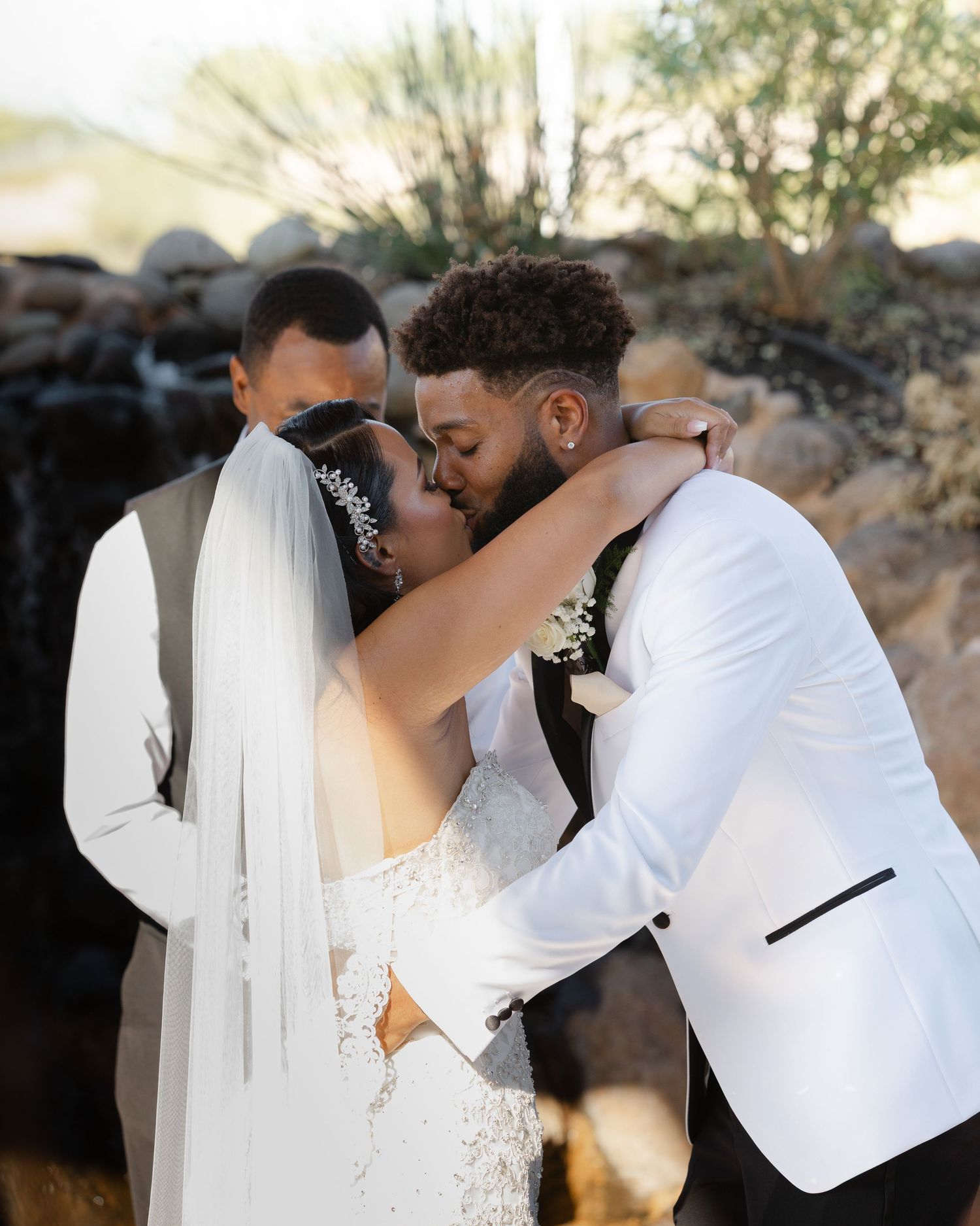 A couple in wedding attire shares a tender embrace during their outdoor sunset photoshoot.