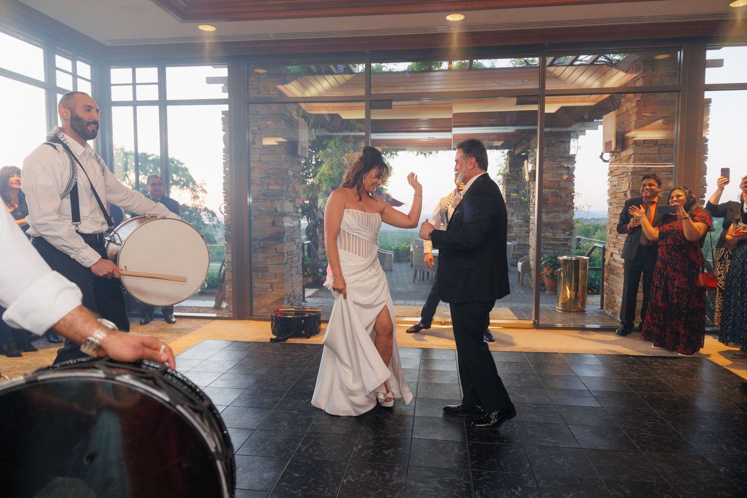 People practicing partner dance moves on a wooden floor in a dance studio with large windows.
