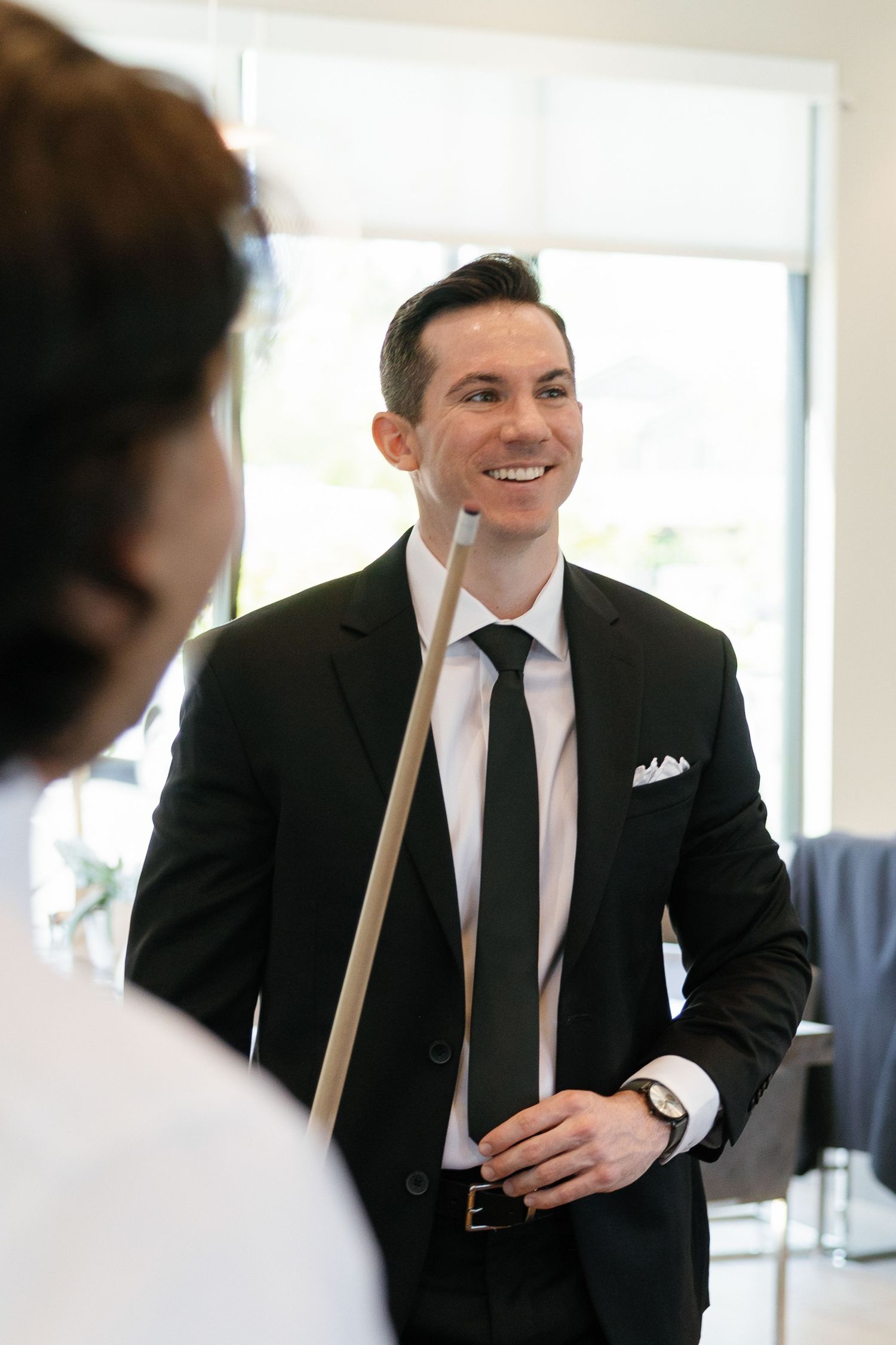 A sequence of photos showing a person in a black suit and tie smiling while holding a white sheet of paper.