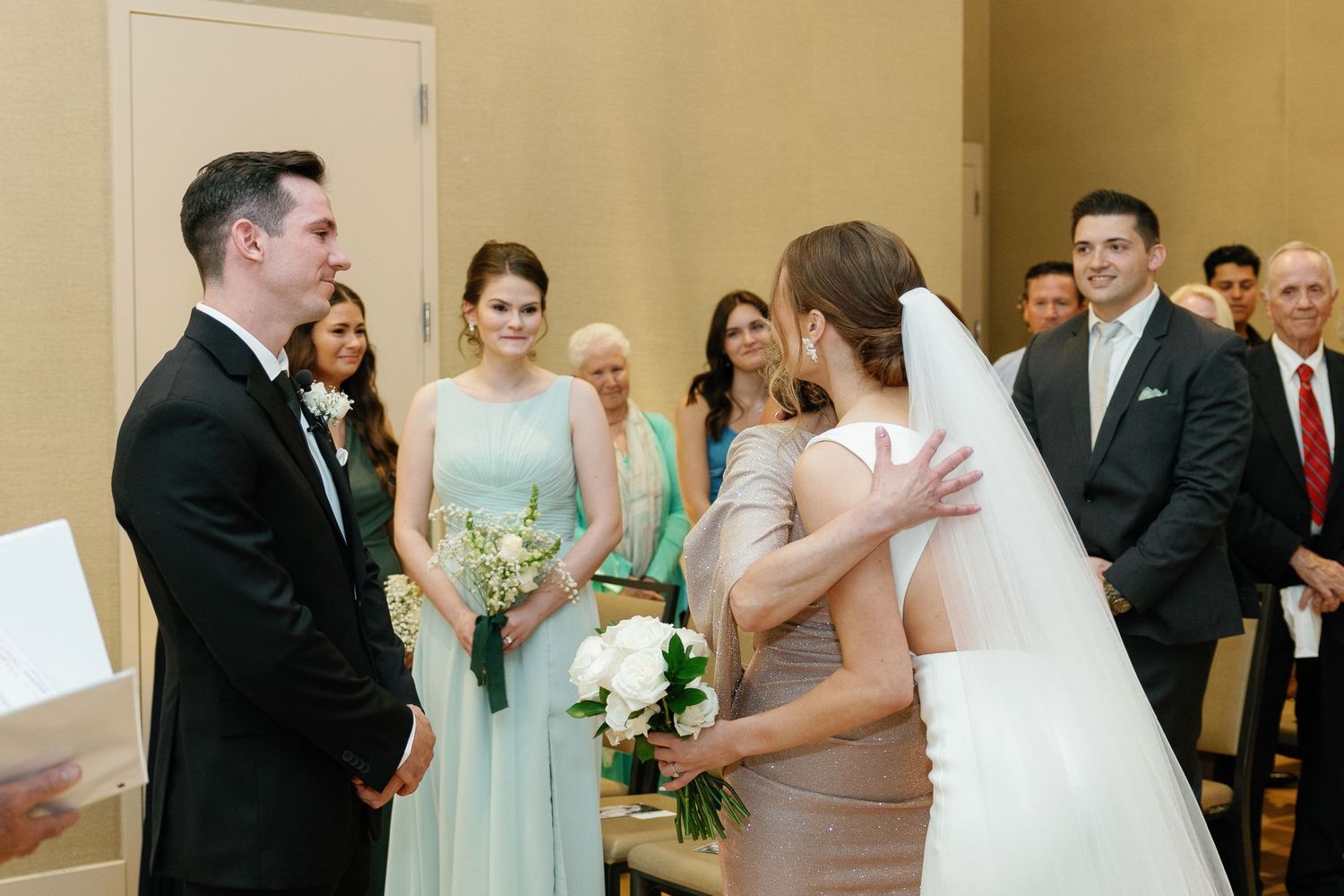 A wedding party in formal attire celebrates during a reception in an elegant indoor venue.