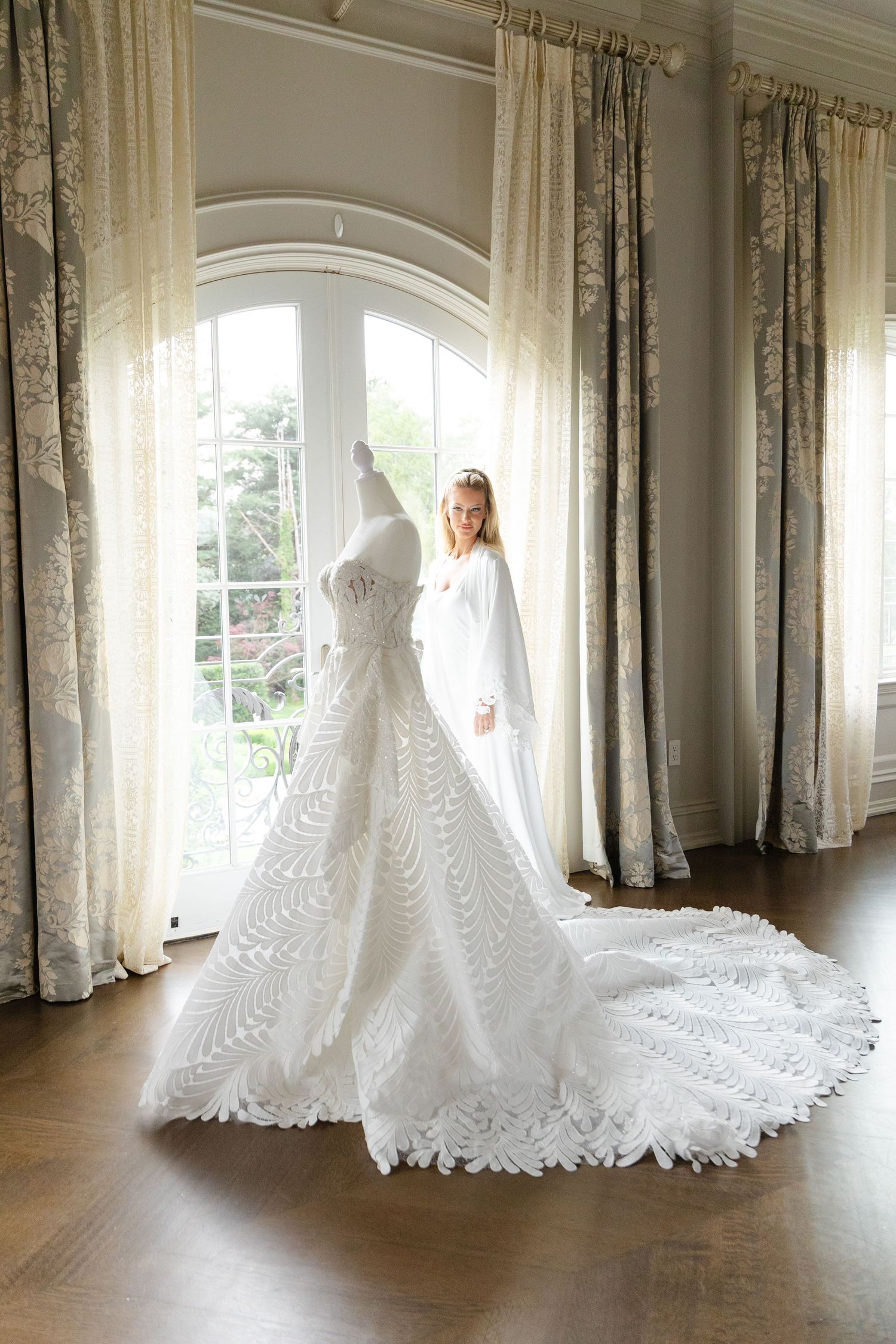A stunning white wedding dress with a dramatic cathedral-length train is photographed in sequence against sunlit windows.