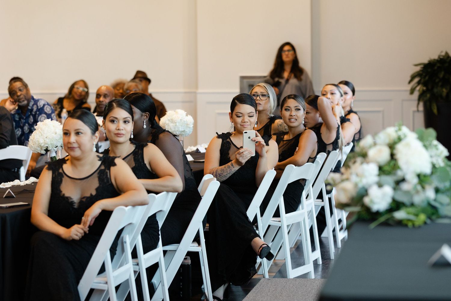 Emotional reactions during a wedding ceremony as guests watch from white chairs in an indoor venue.
