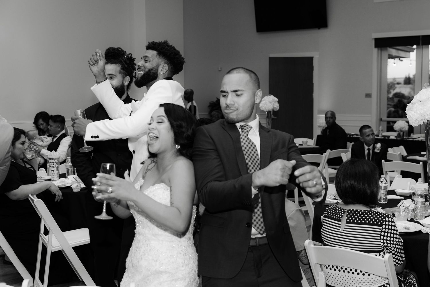 Wedding guests share laughter and conversation during a black and white reception celebration.