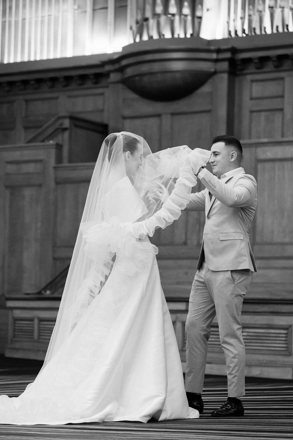 A tender moment between a bride and groom dancing on a grand staircase captured in black and white photography.