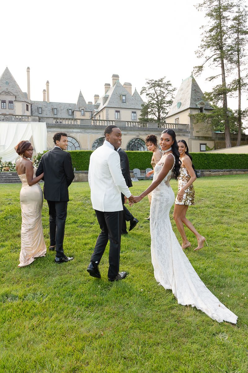 Wedding celebration on a grassy lawn with elegant castle-like building in the background.