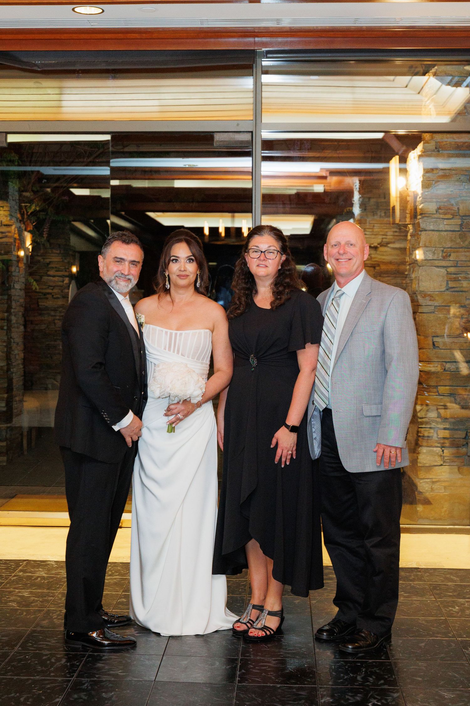 A group poses together at a formal event in front of a stone wall with black flooring.