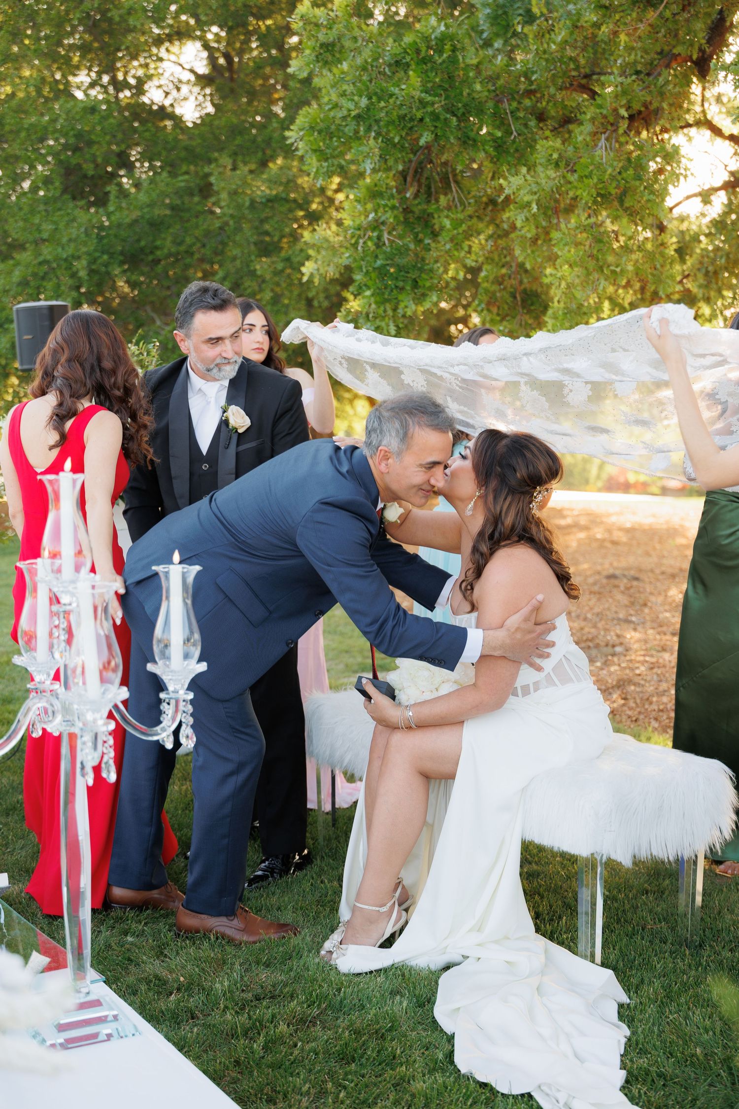 A romantic wedding photo sequence showing the couple dipping and kissing outdoors with white chandeliers and red accents.