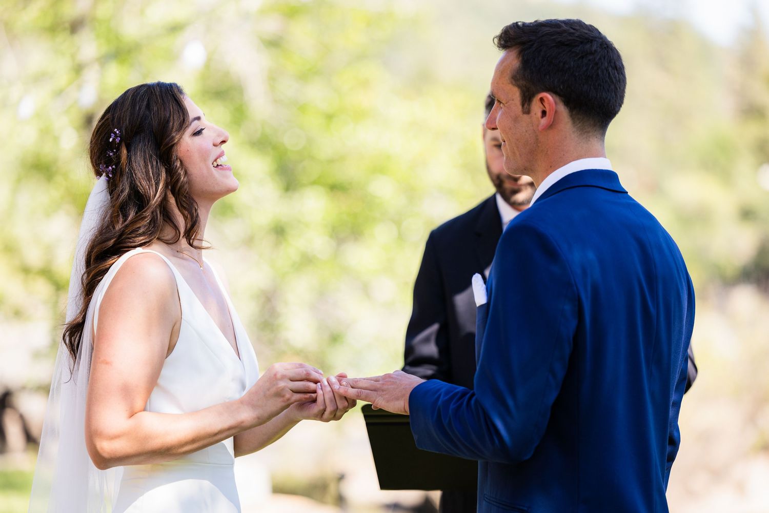 A wedding couple shares romantic moments in a sunny outdoor setting during their special day.