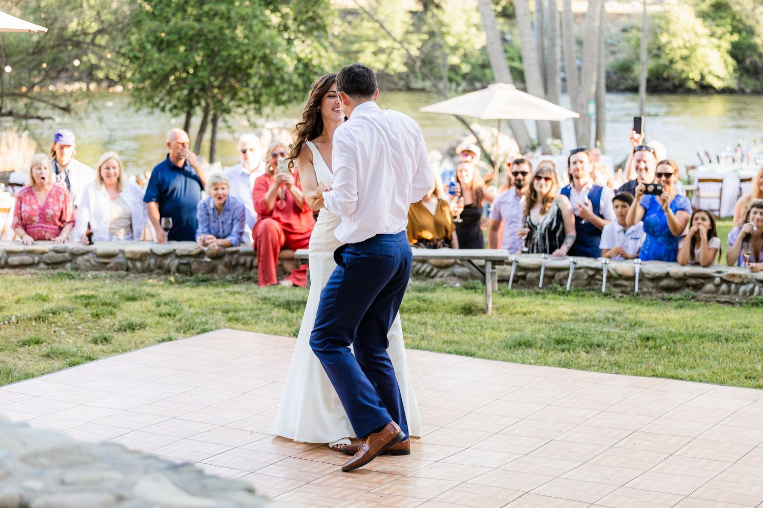 A couple performs their first dance as newlyweds on a white dance floor during an outdoor wedding reception.