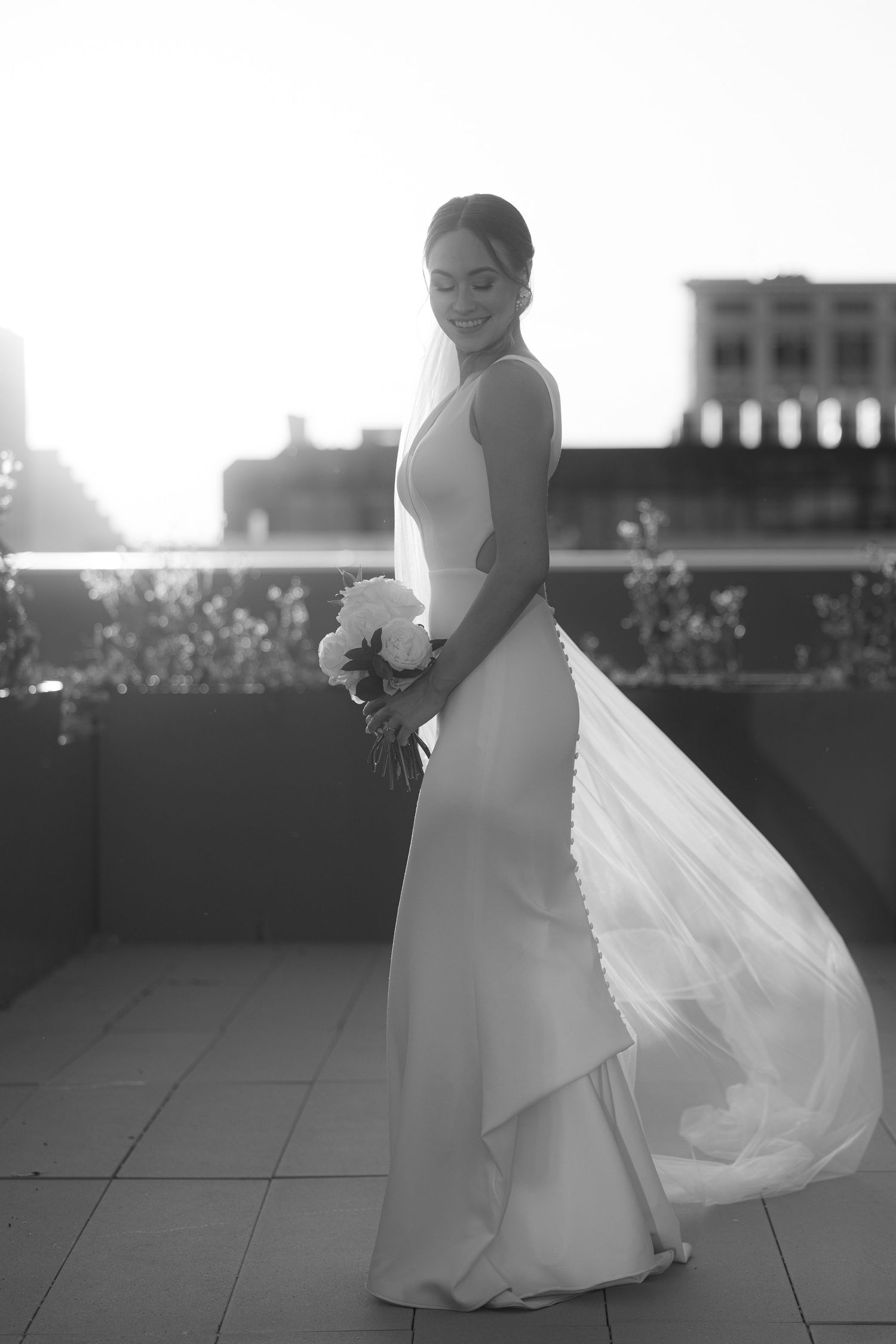 A series of black and white photos showing a bride in a flowing wedding dress on a rooftop at sunset.