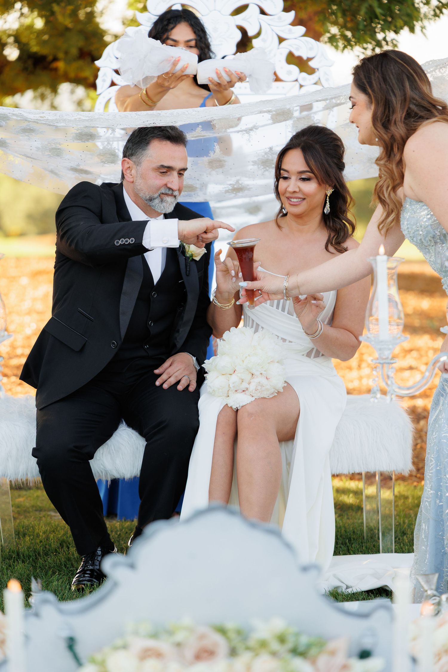 A bride and groom share playful moments during their outdoor wedding photoshoot in warm sunlight.