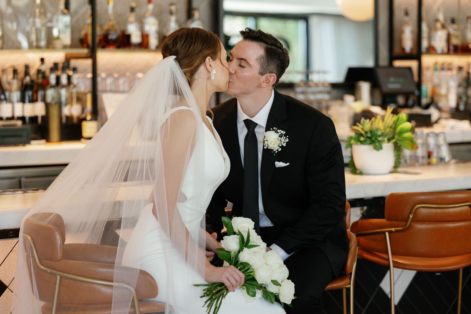 A romantic wedding moment captured at a stylish bar venue with warm lighting and elegant decor.