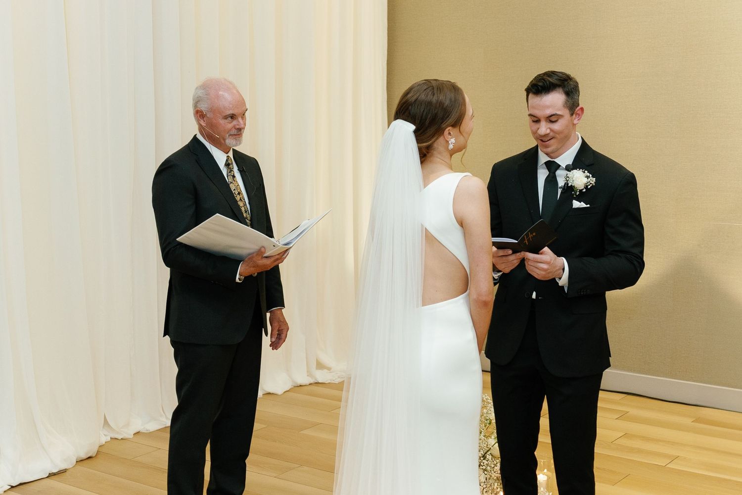 A wedding ceremony sequence shows the couple exchanging vows and rings in front of an officiant in a light-filled room.