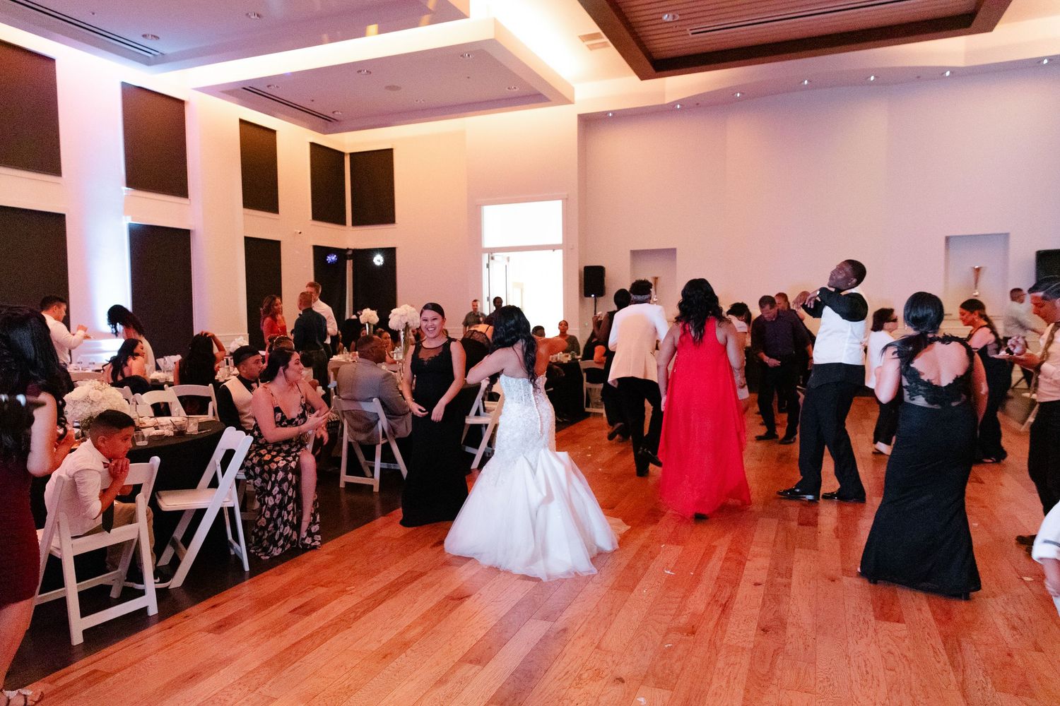 Wedding reception guests dance and celebrate on the dance floor in an elegant ballroom with warm lighting.