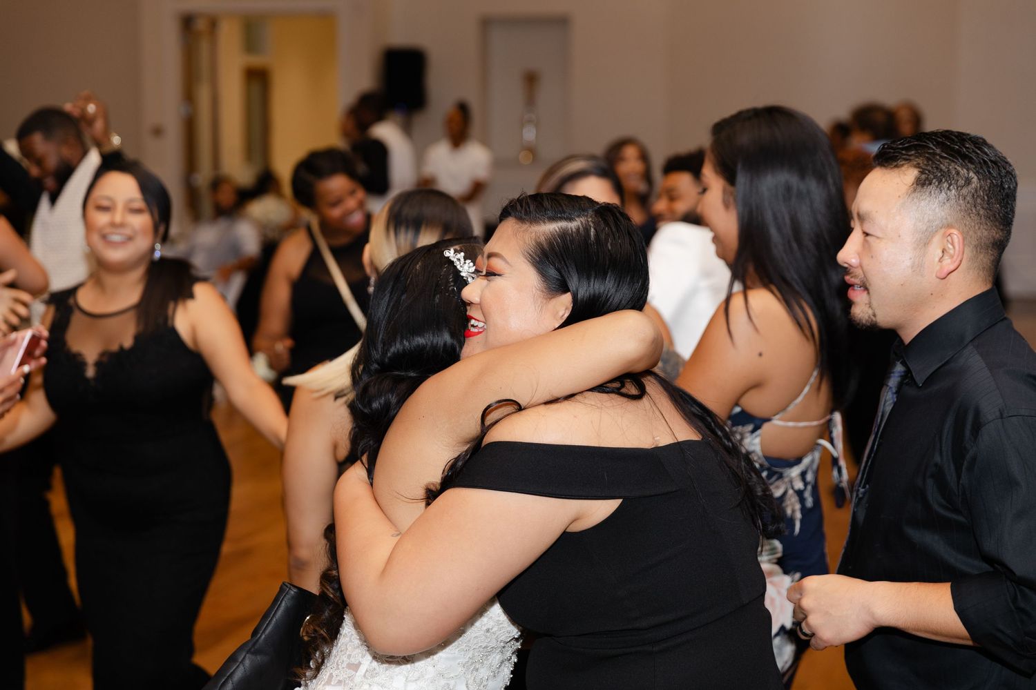 Wedding guests dance and embrace on a crowded dance floor during an elegant reception celebration.