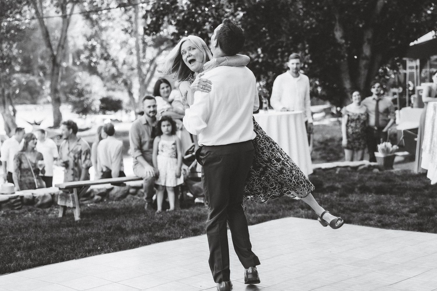 Black and white photo sequence of people dancing and spinning together at an outdoor celebration.