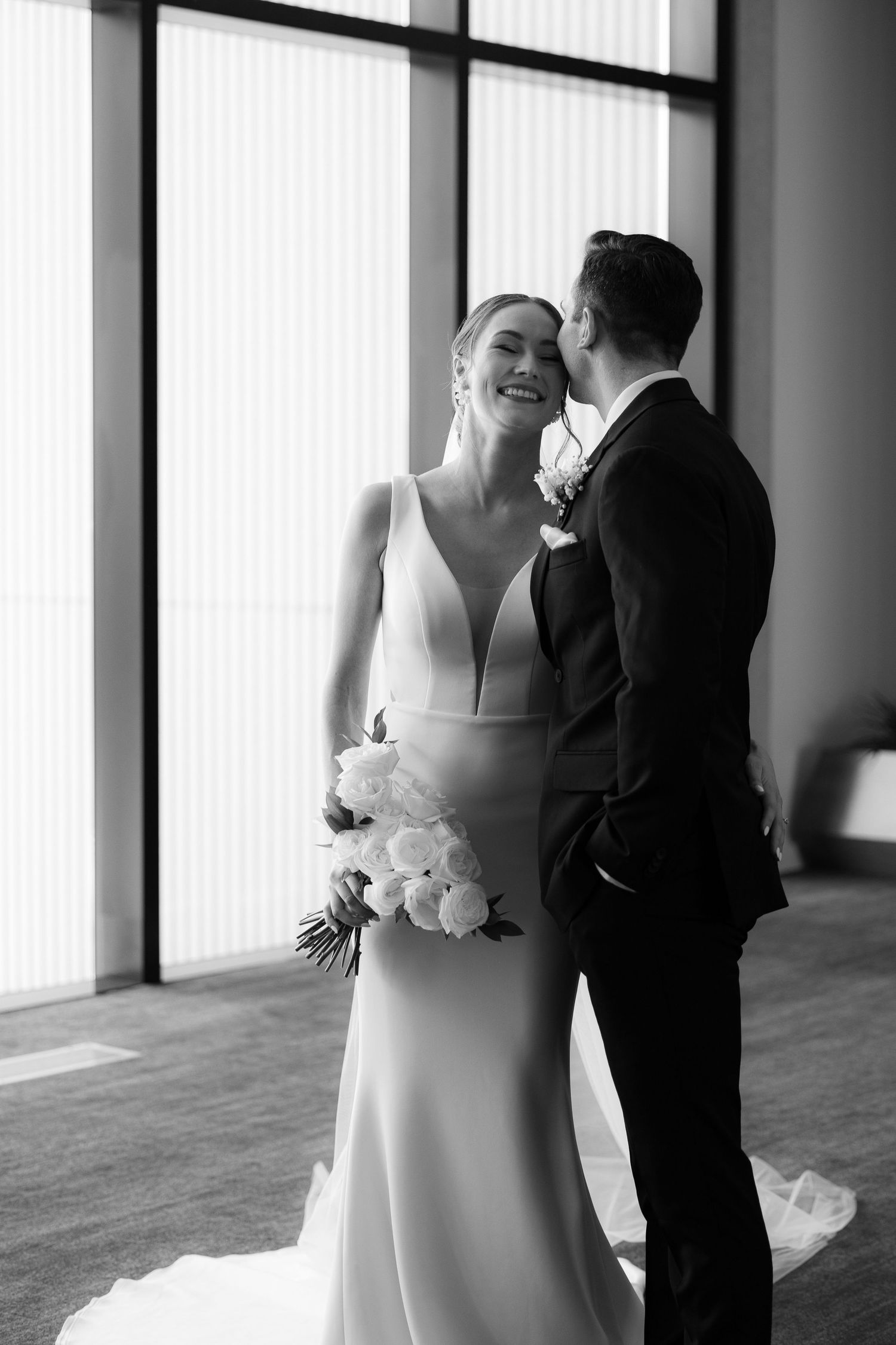 Black and white wedding photo series showing intimate moments between a bride and groom in a columned hallway.