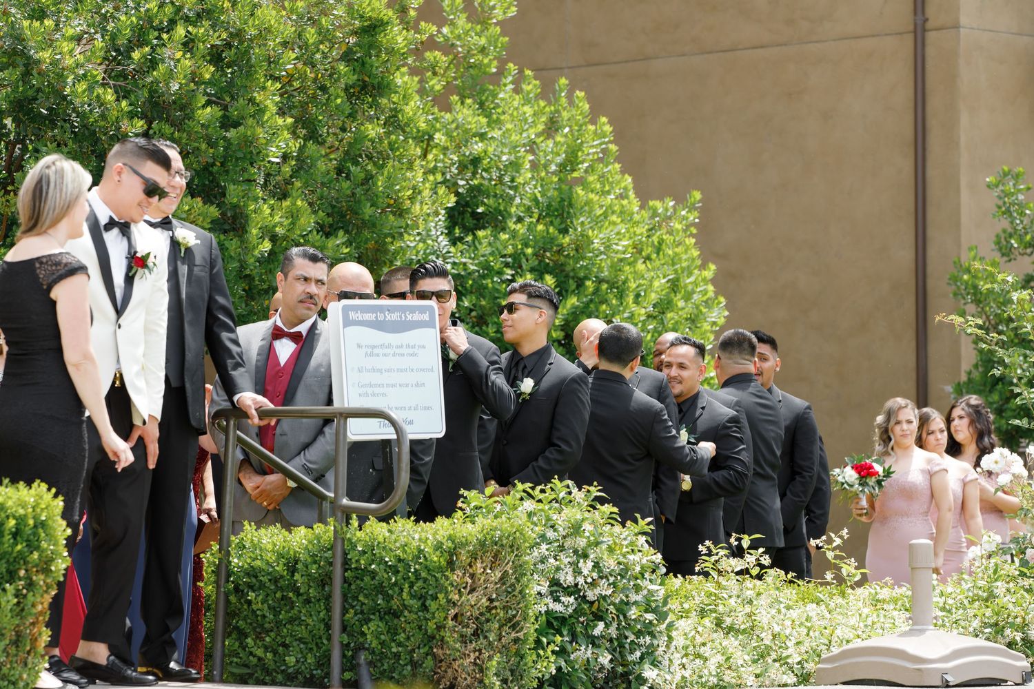 Wedding guests gather in an outdoor garden courtyard for a formal celebration ceremony.