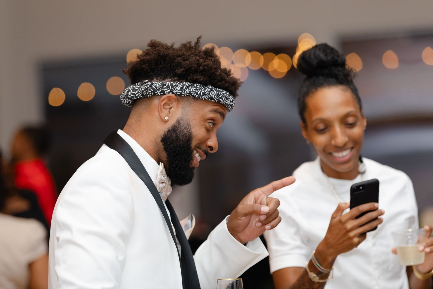 Guests at an elegant wedding reception share joyful moments in formal attire.