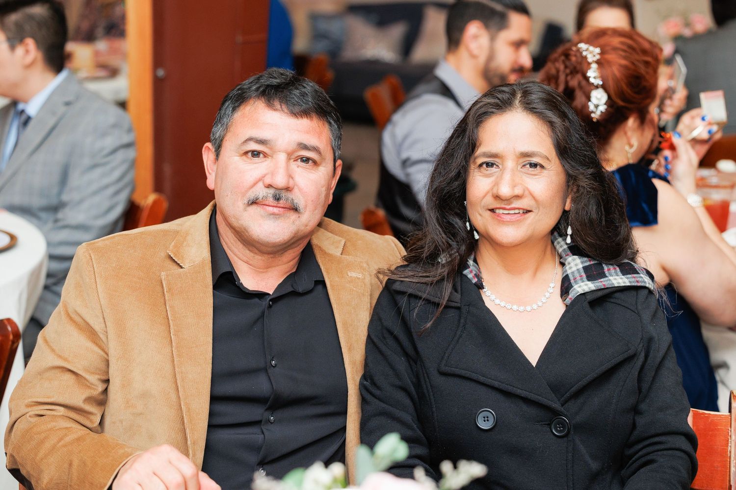 A group of people sitting together and smiling at a social gathering or conference event.