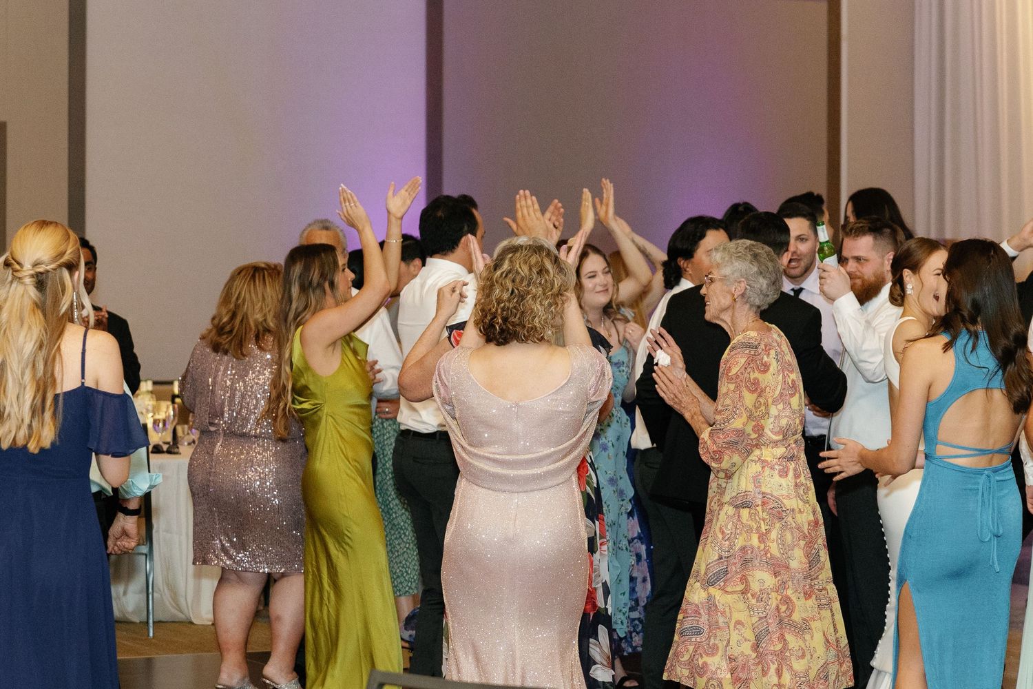 Wedding guests dance and celebrate together on a crowded dance floor during an evening reception.