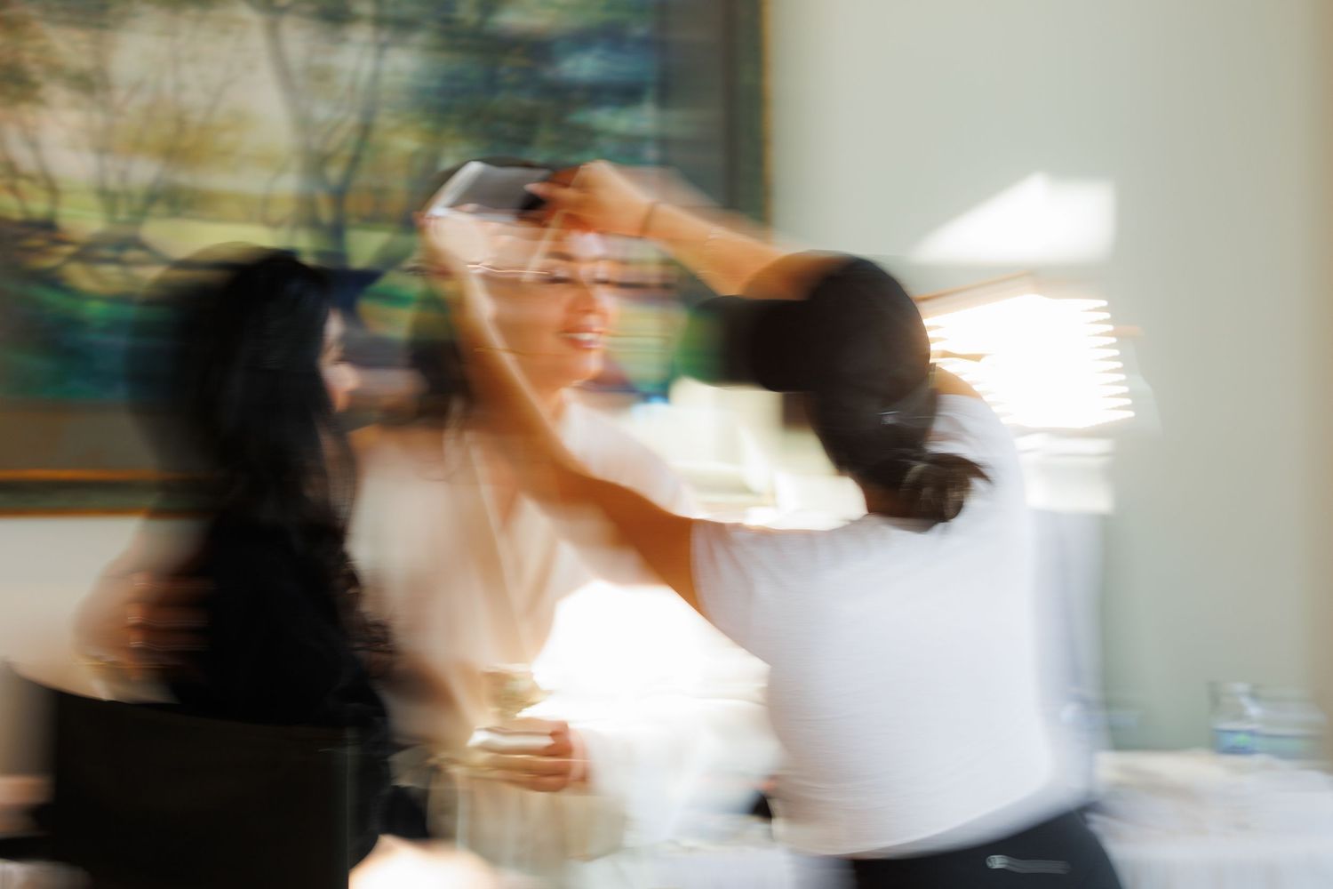 Blurred motion sequence of people moving quickly in a bright white room.