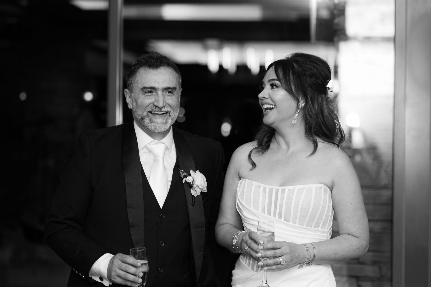 Black and white wedding photograph showing a couple sharing a candid moment together in an intimate setting.