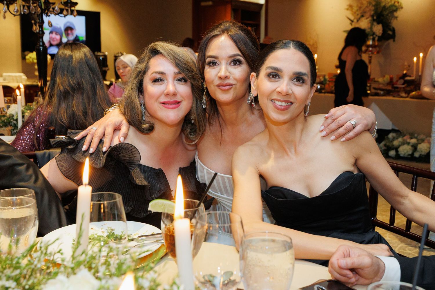 Group of people celebrating at an elegant dinner party with candlelight and formal attire.