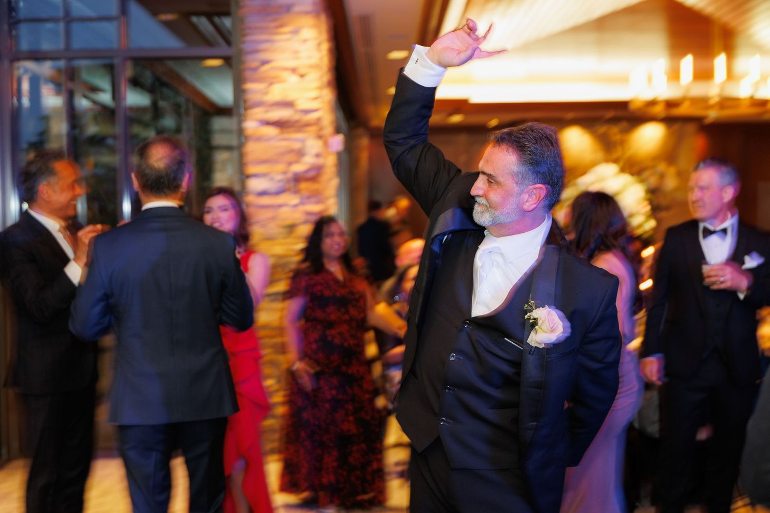 People dance and socialize at an evening wedding reception with warm lighting and decorative elements.